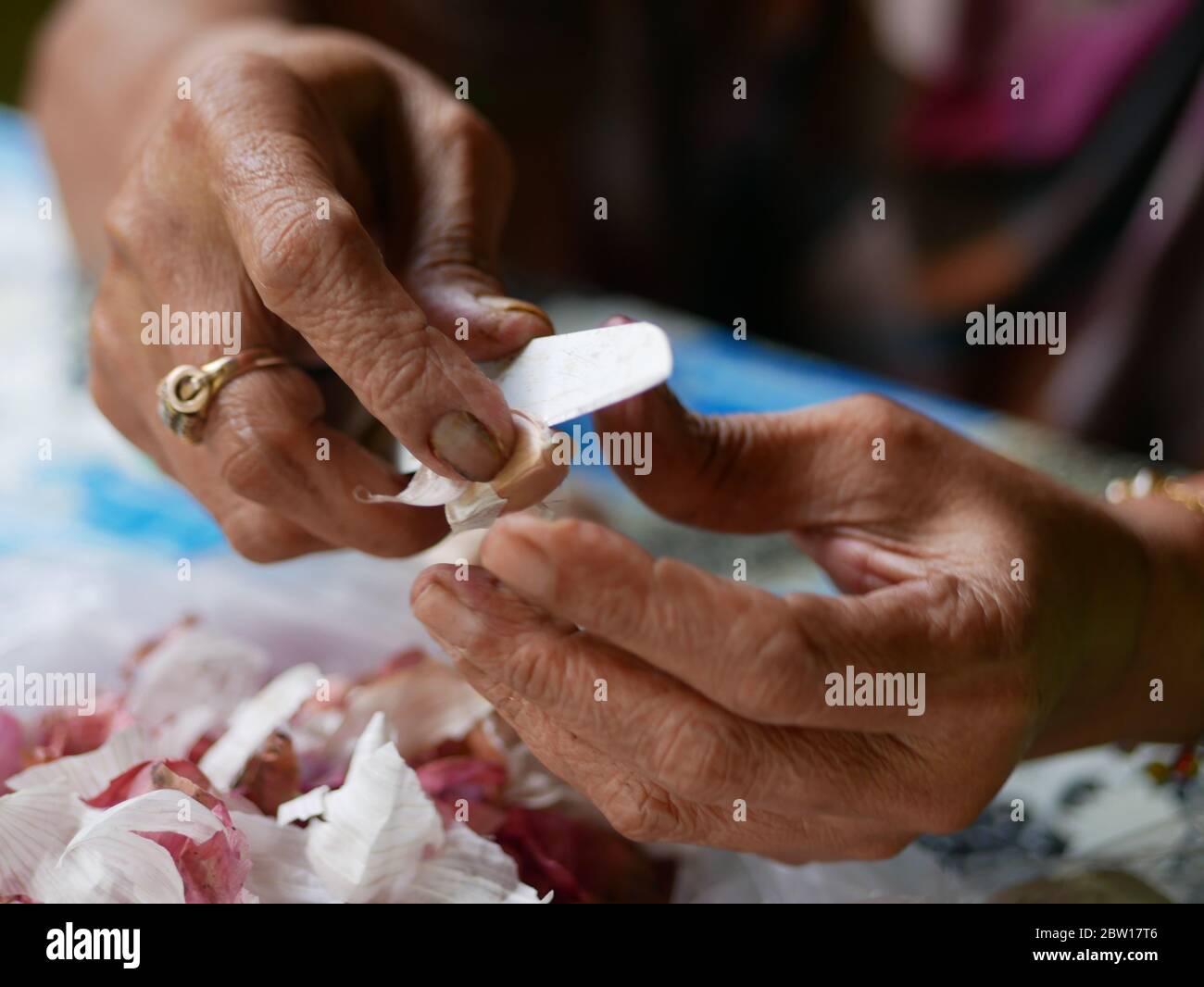 A woman is holding and peeling garlic using a knife Stock Photo - Alamy