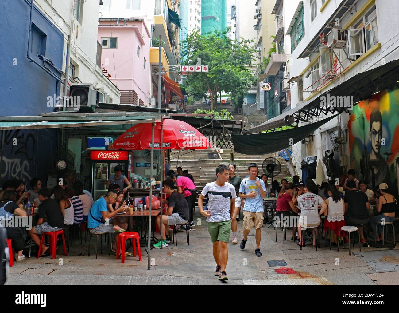 People eating and drinking at outside restaurants and bars on a sunny day on the back streets. Hong Kong Stock Photo