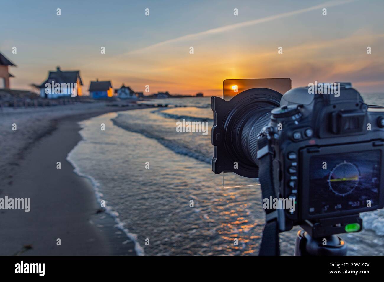Camera DSLR on the tripod with ND filter by sunset photography at Baltic sea, taking a picture of a beautiful sunset, using a gray filter at sunset, s Stock Photo