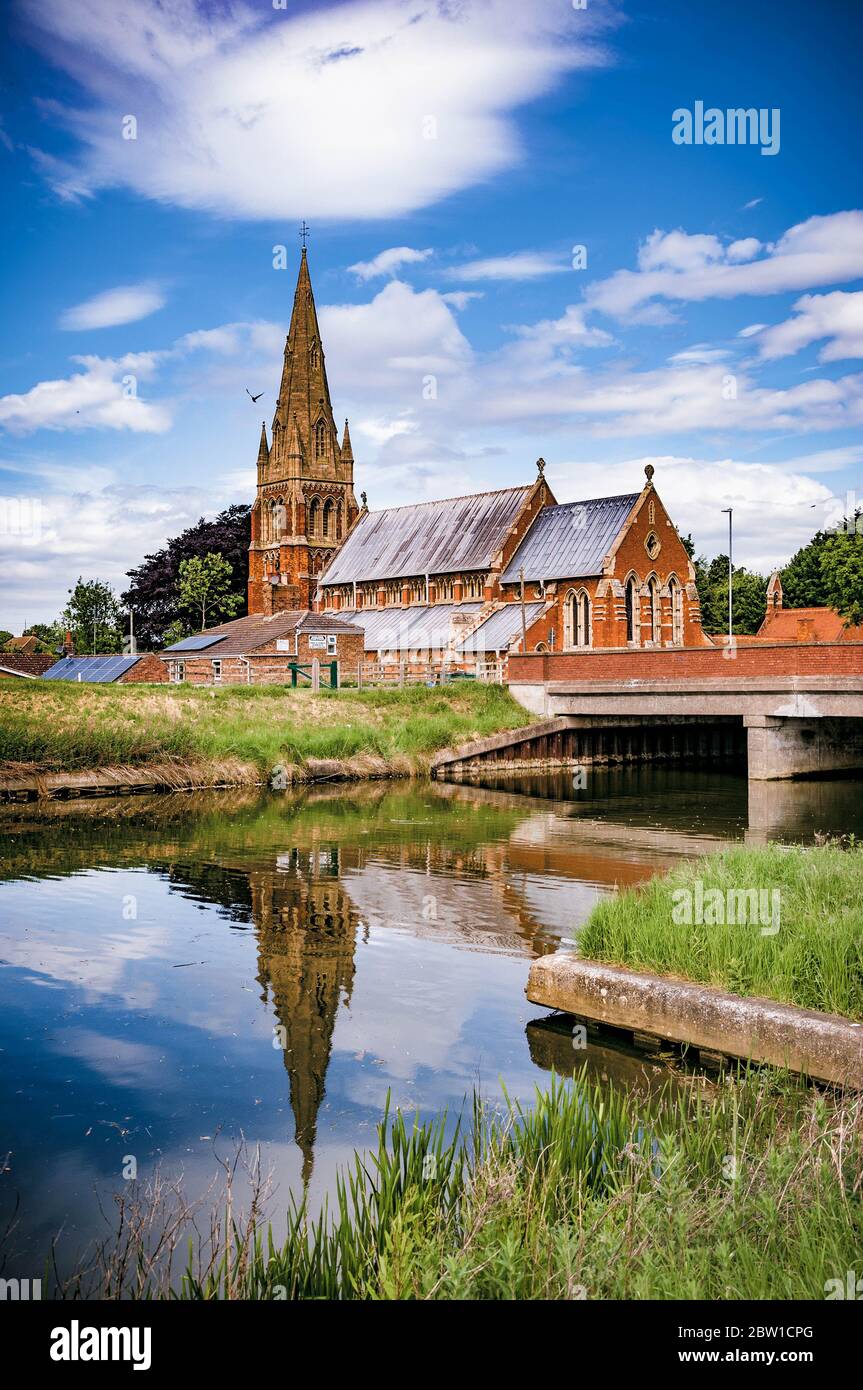 St Paul's Church, Diocese of Lincoln, Fulney, Spalding, Lincolnshire, UK with reflection in the Coronation Channel against a fair weather sky Stock Photo