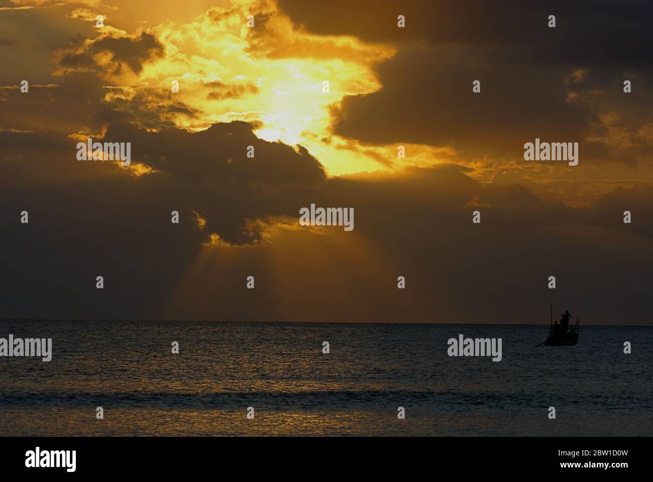 A fishing boat floating on the sea, with rays of light, seen from Batu Termanu, Rote Island, Indonesia. Stock Photo