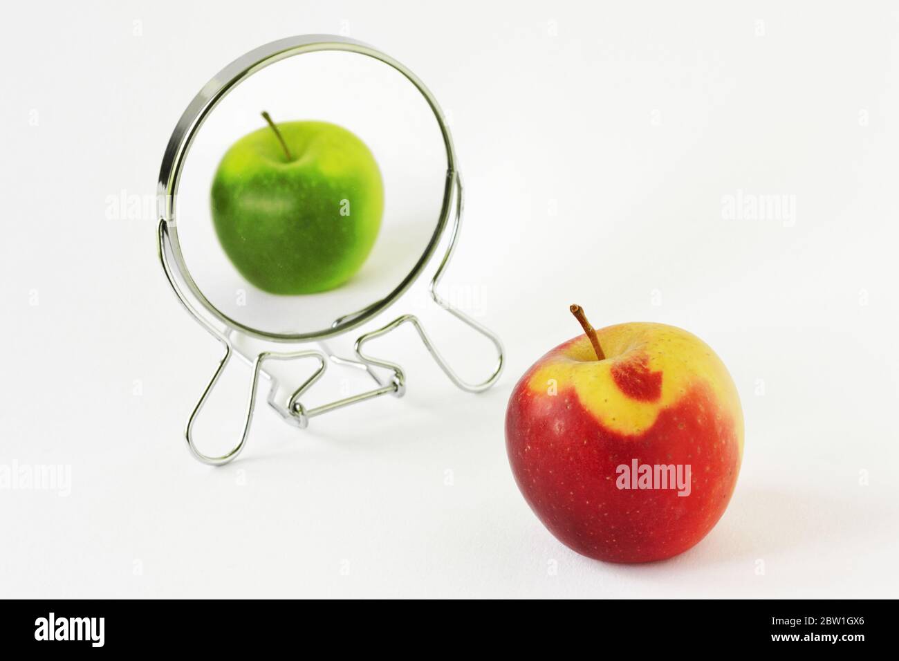 Red apple looking in the mirror and seeing itself as a green apple - Concept of daltonism and color blindness Stock Photo