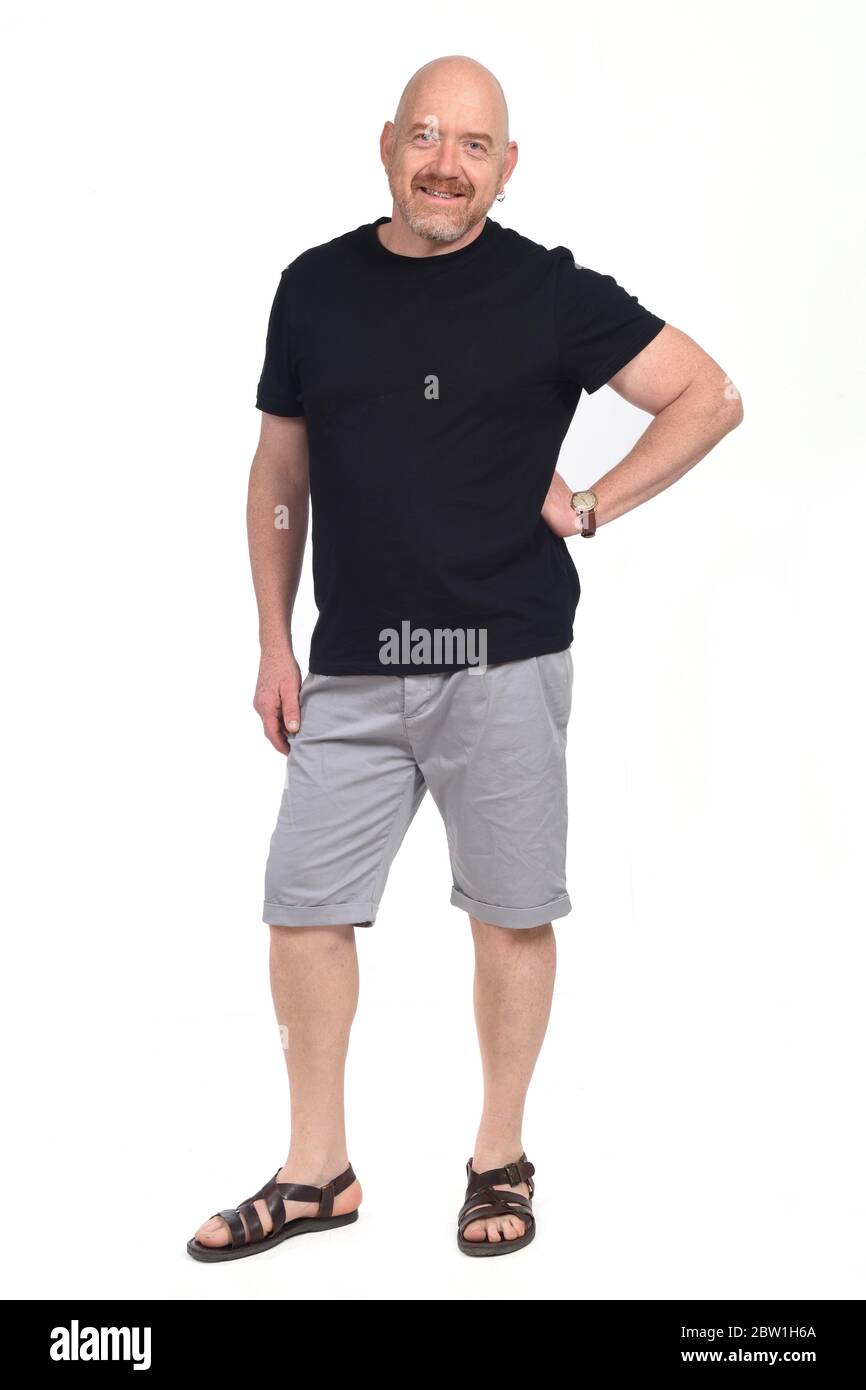 Bald man with sandals t-shirt and shorts, hand on hip looking at camera on whithe background Stock Photo
