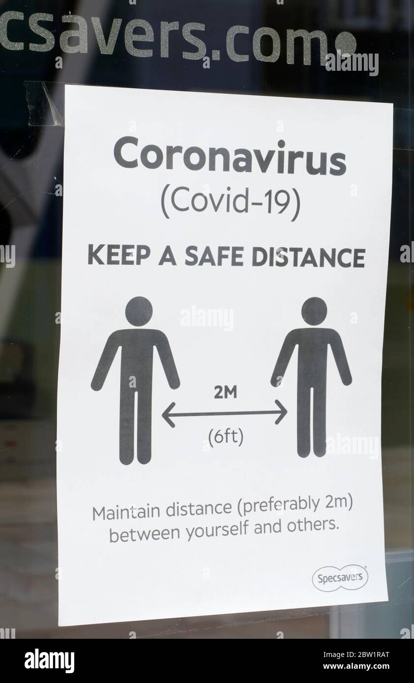 Notice on entrance door to Specsavers opticians asking customers to keep a safe distance during the Coronavirus / Covid-19 restrictions Stock Photo
