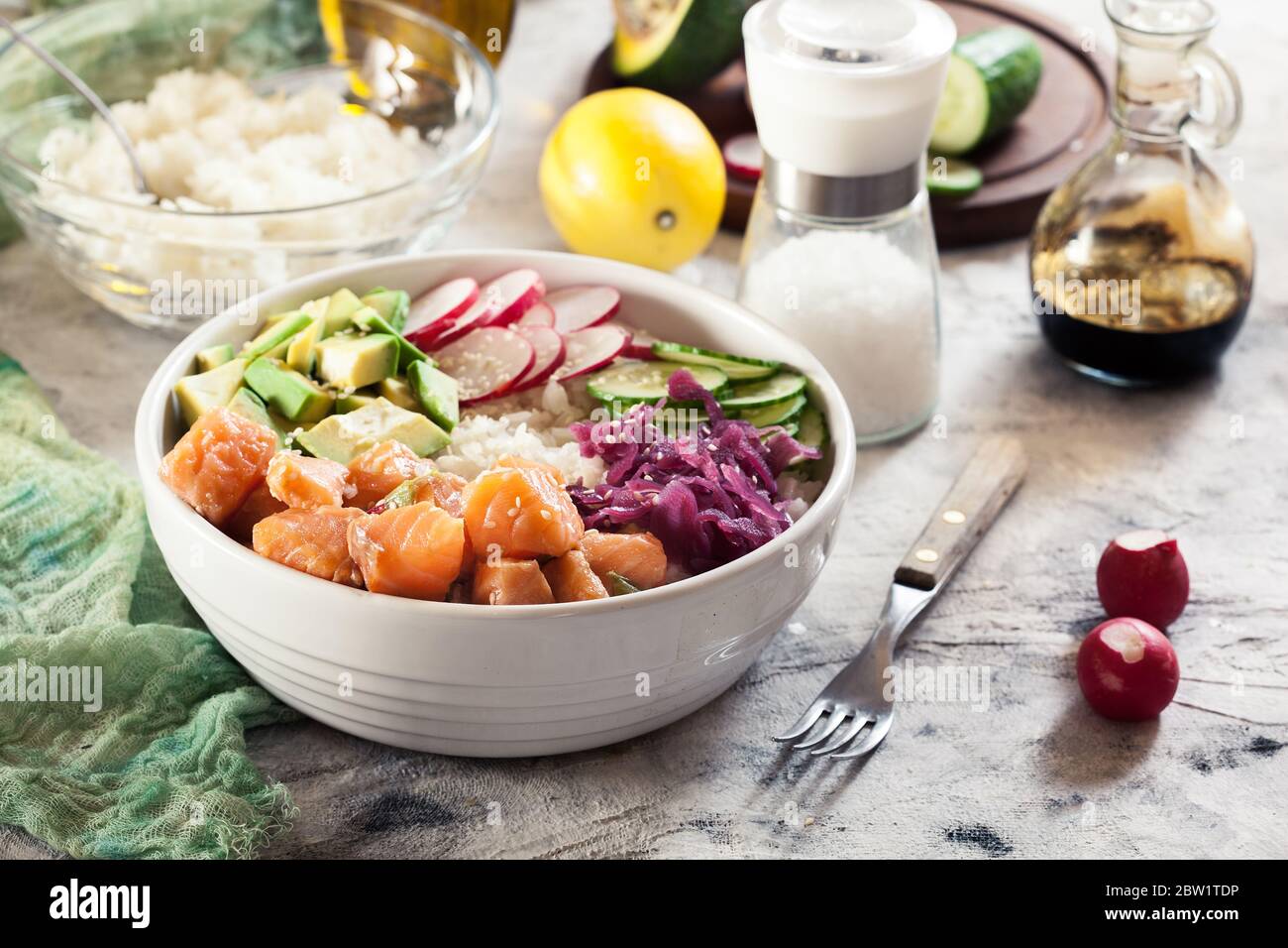 Poke bowl, traditional Hawaiian raw fish salad with rice, avocado, cucumber and radish on bright background Stock Photo