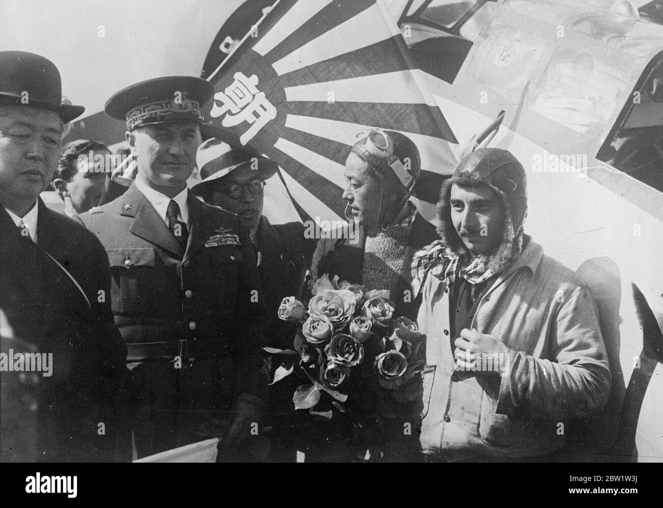 Record-breaking Japanese airmen received tremendous welcome in Rome. Landing at the Littorio Airport, Rome on their record-breaking 94 hour dash from Tokyo to London the Japanese airmen, Masaaki Iinuma, and Kenji Tsukakoshi, received a tremendous welcome from crowds gathered to welcome them. From Rome they went to complete the journey to London in an proceeded time 10,000 miles in 94 hours. Photo shows: the Japanese airmen with their plane Divine Wind [Mitsubishi Ki-15 Karigane aircraft, name: Kamikaze, registration J-BAAI] on arrival at the Littorio Airport, Rome. Iinuma, the 27-year-old pilo Stock Photo