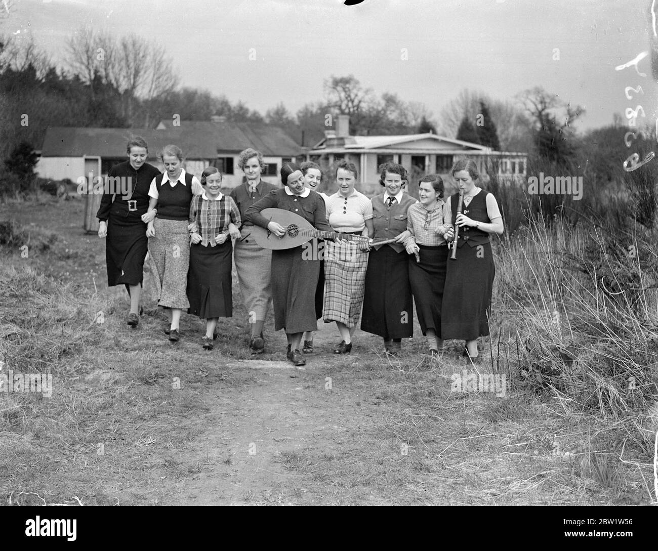 Fräuleins in the New Forest good will camp at Godshill. Girl members of the Hitler Youth Movement - students, clerks and factory hands between the ages of 18 and 25 - are attending a second annual camp organised to promote Anglo - German friendship at Godshill in the New Forest in Hampshire. They are to entertain a party of English girls over the weekend. Young girls from England are attending a similar camp in Germany. Photo shows: the German girls walking in the New Forest with their mandoline. 10 April 1937 Stock Photo