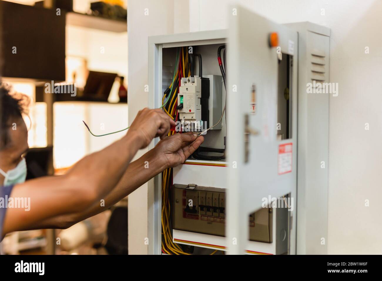 electrician-with-medical-mask-works-with-electric-cable-wires-of-switch-box-2BW1W6F.jpg