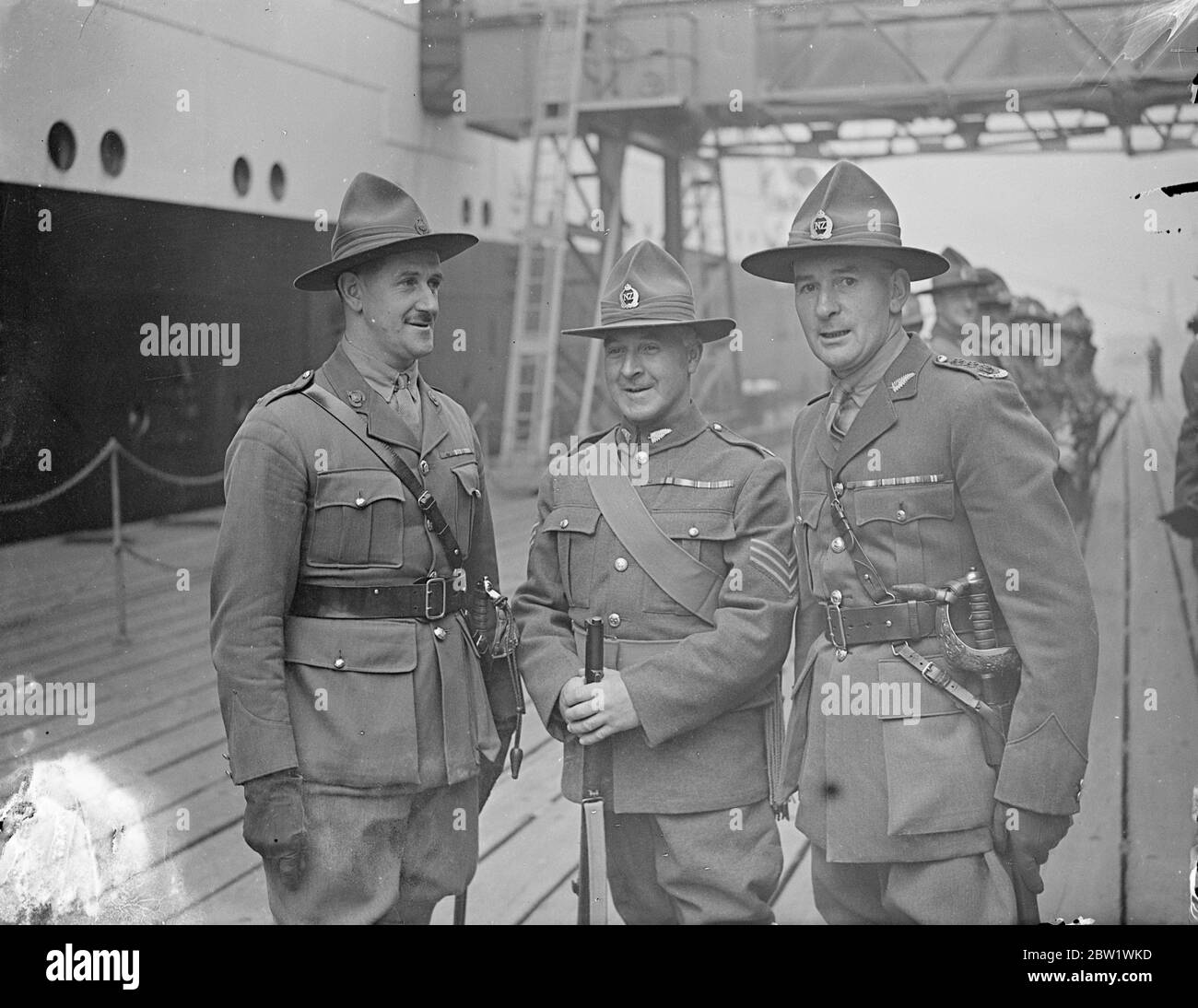 Three VCs. New Zealand Coronation contingent arrives in England. With three VCs included in their number, New Zealand's contingent for the Coronation arrived at Tilbury aboard the 'Rangitiki. The continued numbers 50 men, comprising officers and other ranks of the army and air force, and is under the command of Maj N W McD Weir, of the New Zealand Staff Corps. Photo shows, the three VCs on arrival at Tilbury. Left to right, Captain R W Andrews, also a member of the Staff Corps and Second-In-Command Sgt James Crichton and Capt S Freikleton. 19 April 1937 Stock Photo