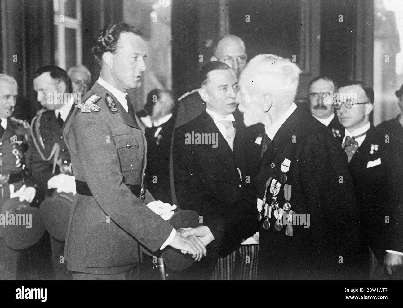 King Leopold greets man who escaped war sentence of death at Nurse Cavell Memorial service. In the room of the Senate in Brussels where Nurse Cavell and 35 Belgians were condemned to death in 1915 for helping refugee soldiers, King Leopold attended a ceremony in their memory. Photo shows, King Leopold shaking hands with a man he was condemned to death by the Germans, but escaped, at the Memorial service in Brussels. 19 April 1937 Stock Photo