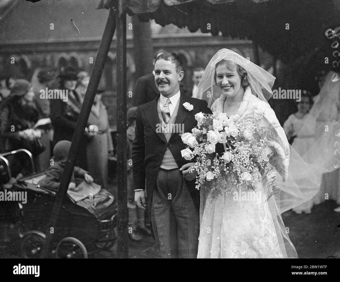 Radio actor weds actress in London. Bishop of London officiate. Mr Norman Shelley, the radio actor, and Miss Monica Brett, the actress, were married at St Stephen's Parish Church, Gloucester Road, Kensington. The Bishop of London, Dr Winnington Ingram officiated, and Lesley Woodgate, the BBC conductor, played the organ. Photo shows, the bridegroom lifting the bride's veil as they faced the photographer after the ceremony 16 April 1937 Stock Photo