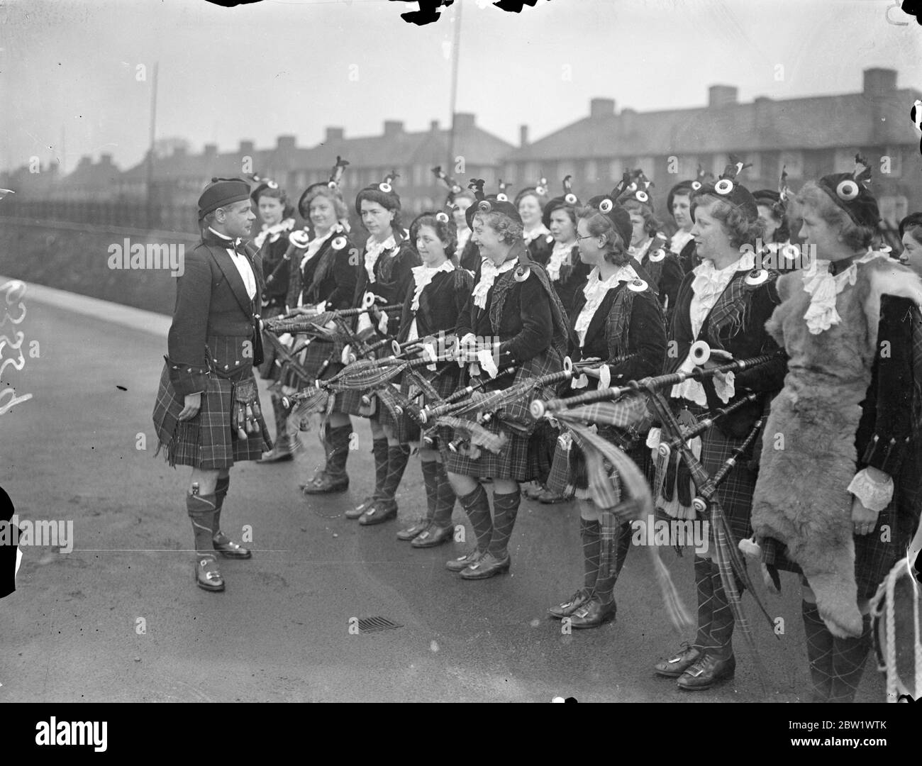 Dagenham Girl Pipers welcomed their new 'Chieftain'. Pipe Maj George Greenfield of the Royal Scots, recognised as one of Scotland's greatest experts on the bagpipes and Highland Dances, was met at Heathway station (District Railway) by the band of the Dagenham Girl Pipers in full uniform when he arrived at Dagenham, Essex, to become Pipe Maj of the Girl Pipers. George Greenfield enlisted in the Royal Scot as a boy piper and has now completed his 21 years service. As 'Chieftain' of the Dagenham Girl Pipers he will be responsible for the piping and dancing instruction of over 50 girls. Photo sho Stock Photo