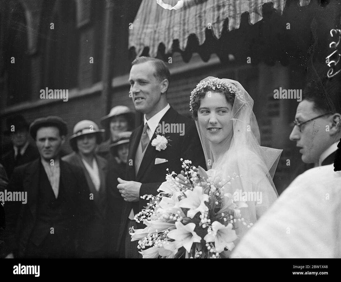 Married at the same time as Duke of Windsor. London wedding rush. Among the rush of London couples who arrange their wedding to take place at the same time as that of the Duke and Duchess of Windsor were Mr J. G. Lockhart and Miss M. C. M. Gordon daughter of the late Brigadier General A. F. Gordon D. S. O., who were married at St Mary's, Cadogan Square. Photo Shows: the bride and bridegroom after the ceremony. 3 June 1937 Stock Photo