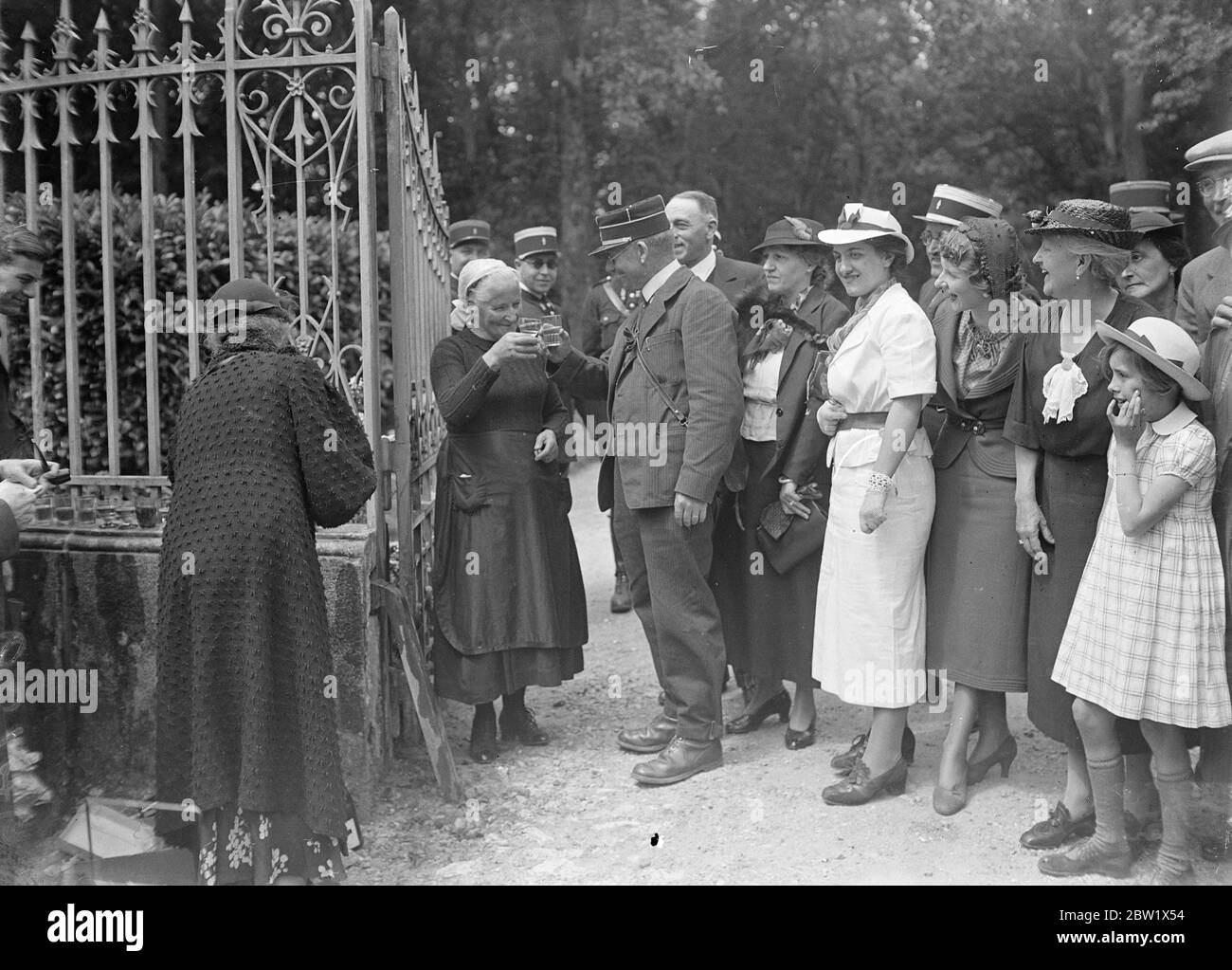 Villagers toast the Duke of Windsor and his bride. In champagne specially sent down by the Duke of Windsor, villagers of the small neighbouring village of Monts toasted the Duke of Windsor and his bride, Mrs Wallis Warfield, at the gates of the Château de Candé near Tours France. Photo shows: the lodge-keeper at Chateau de Cande Mlle Prosper, toasting the Duke of Windsor and his bride with the village postman. 3 June 1937 Stock Photo