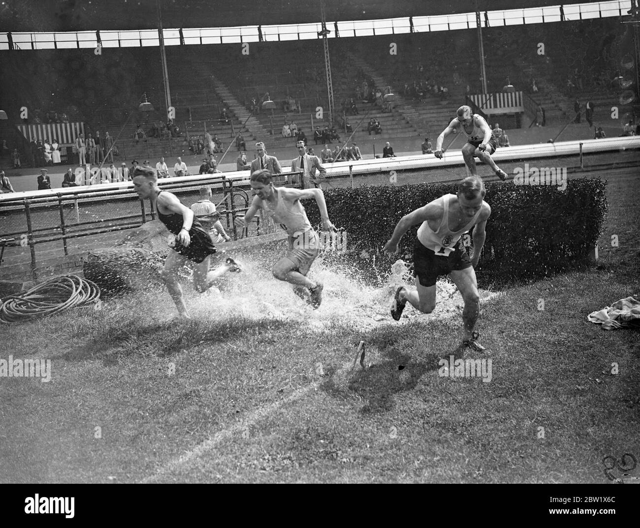 Through the water into miles Steeplechase at White City. Leading athletes competed in their Kinnaird Trophy tournament at the White City, London. Photo shows, taking the water jump in the two-mile steeplechase. 29 May 1937 Stock Photo