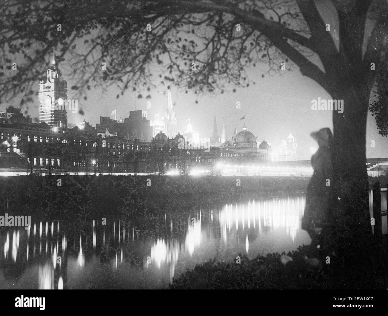 Melbourne a fairy city during Coronation celebrations. Melbourne, Australia, presented a beautiful night spectacle when the city was eliminated by an elaborate scheme of floodlighting in celebration of the Coronation. Photo shows, a view of flood lighted Melbourne seen across the River Yarra. Flinders Street railway station is in the foreground. 27 May 1937 Stock Photo