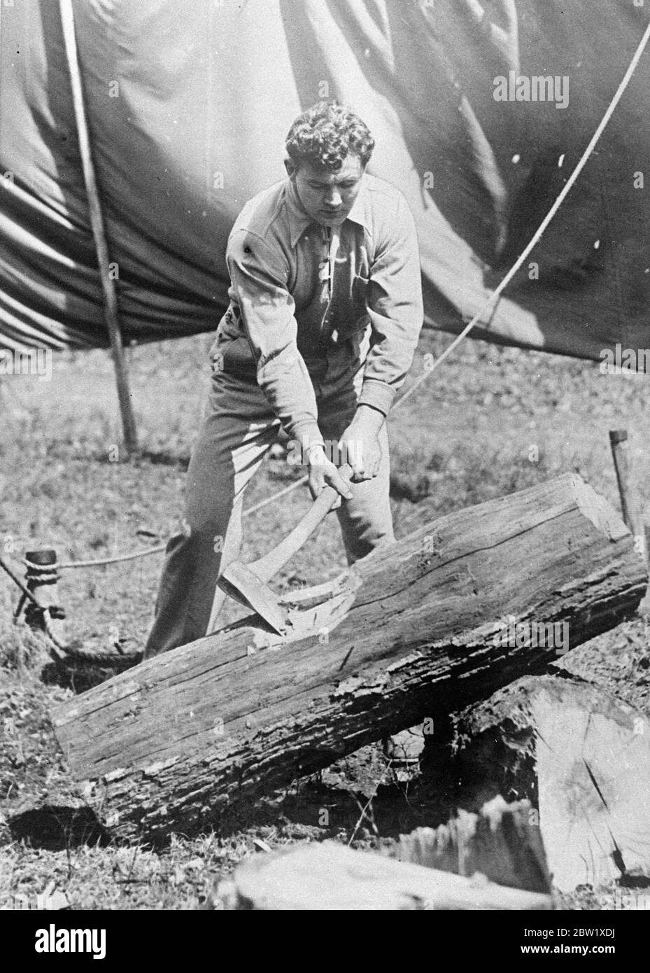 World's champion trains to defend title. James J. Braddock, world's heavyweight boxing champion, is training at Grand Beach, Michigan, to defend his title against Joe Lewis in Chicago next month. Photo shows: James J. Braddock chopping wood as part of his training at his Michigan camp. 26 May 1937 [?] Stock Photo