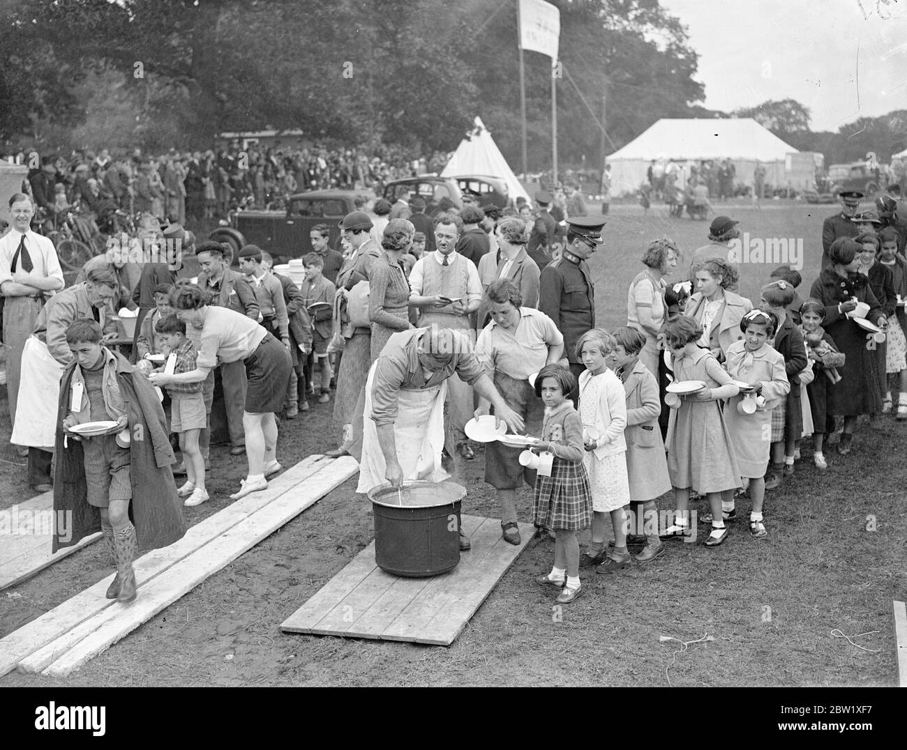 Refugee children find happiness far from Civil War. Encamped at Southampton. After dissing barking from the liner and a banner which brought them from the Civil War zone at Bilbao, the 4000 Spanish refugee children were taken to the special camp outside Southampton and given their first decent meal in many months. They have been existing on black bread and in perpetual fear of a raids. Photo shows, laughing refugee children enjoying their first decent meal months at the Southampton camp today (Sunday). 23 May 1937 Stock Photo