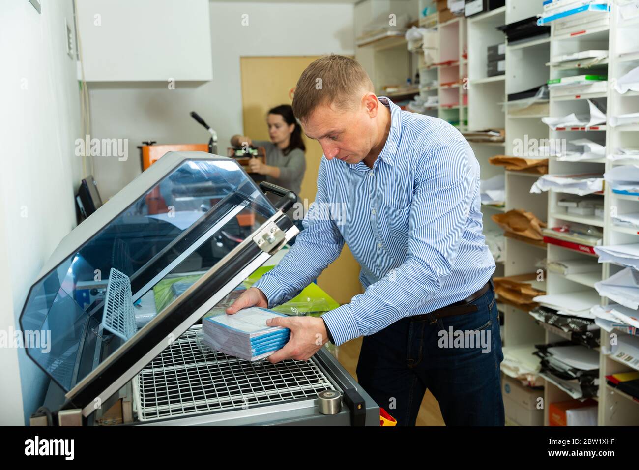 Worker packs notebooks in a vacuum packing Stock Photo