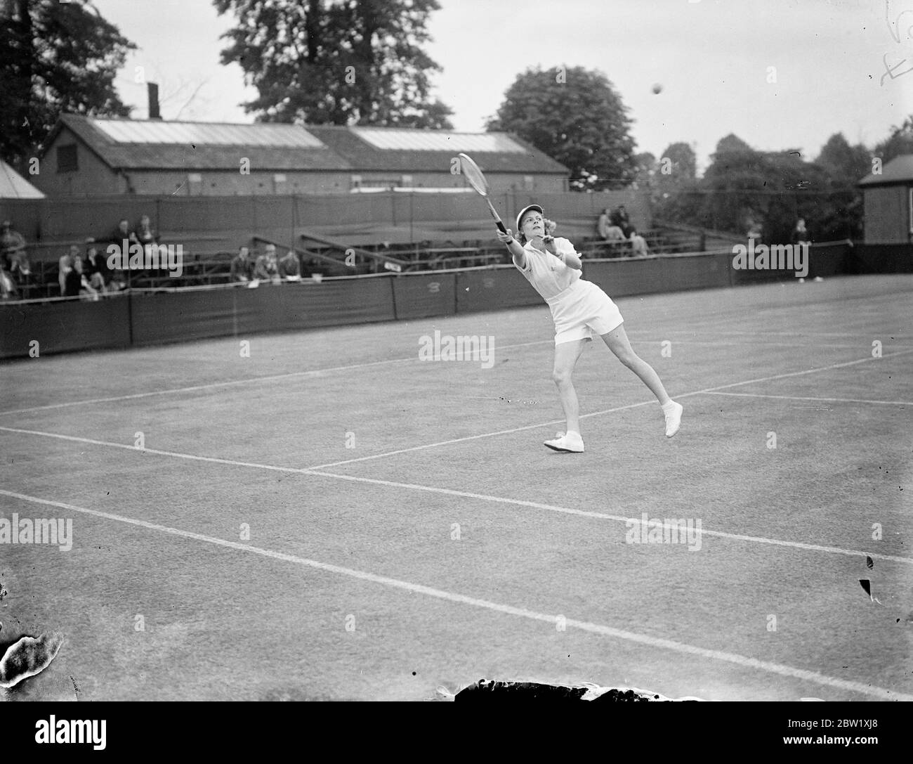 American woman champion fights 1 1/2 hour match in Surbiton Championships. After a hard match lasting over an hour and a half, Miss Alice Marble, the American champion, defeated Miss Thompson in the women's singles of the Surrey lawn tennis Championships at Surbiton, Surrey. Photo shows, Miss Alice Marble leaving for a high shot during her match against Miss Thompson. 20 May 1937 Stock Photo