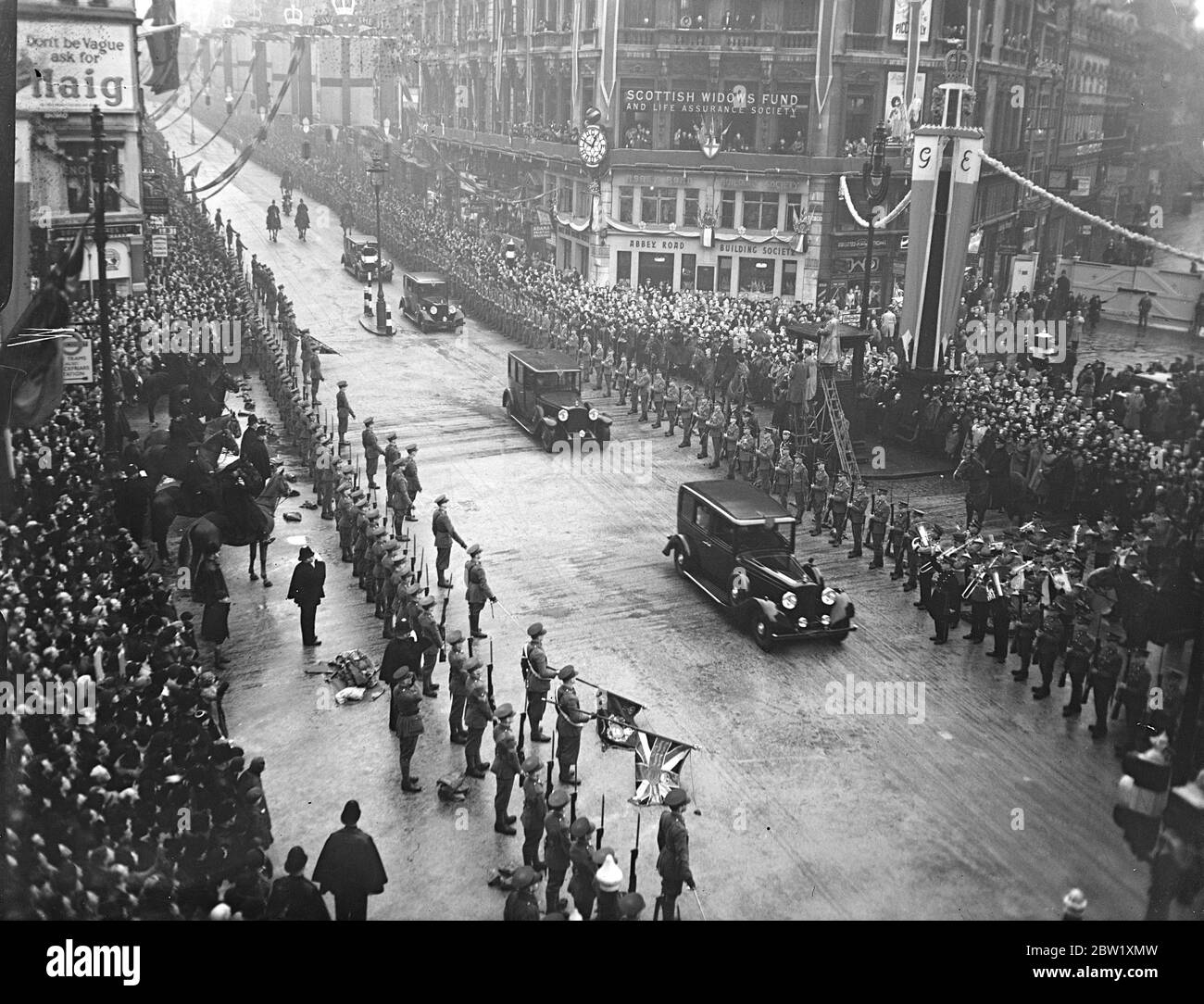 King and Queen drive to Guildhall in closed car. Cheered by many thousands of people despite the dull weather, the King and Queen drove from Buckingham Palace to the Guildhall to lunch with the Lord Mayor , Sir George Broadbridge and the city Corporation. Because of the rain, a close car was used, and escort was dispensed with and the Temple Bar ceremony was cancelled. Photo shows, the Royal car crossing Ludgate Circus. 19 May 1937 Stock Photo