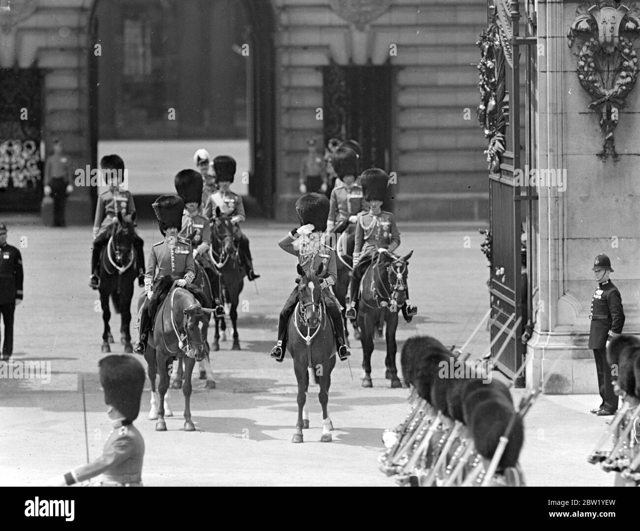 King takes salute at Buckingham Palace. For the first time since his succession the King rode in procession from Buckingham Palace to attend the ceremony of Trooping the Colour on the Horse Guards Parade. The King was accompanied by the Duke of Gloucester and Kent and Prince Arthur of Connaught. The Queen and other members of the Royal Family watched the ceremony. The colour of the first Battalion Coldstream Guards was trooped. Photo shows: the King taking the salute as the Guards this march past Buckingham Palace. 9 June 1937 Stock Photo