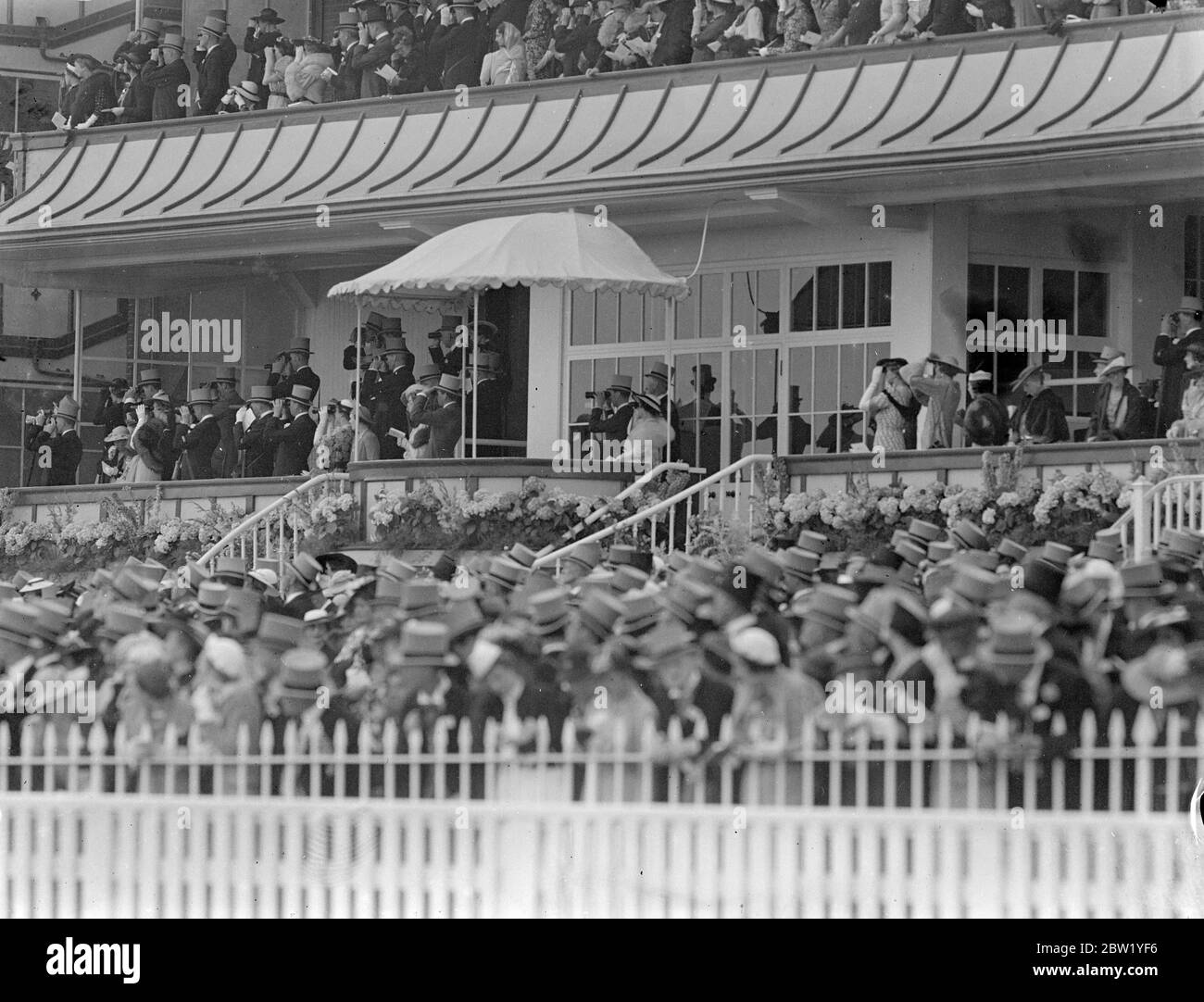 King and Queen as Royal party at Ascot. The King and Queen, accompanied by other members of the Royal family. Attending the opening meeting at Ascot. Photo shows, the King and Queen watching the racing from the Royal Box at Ascot. 15 June 1937 Stock Photo