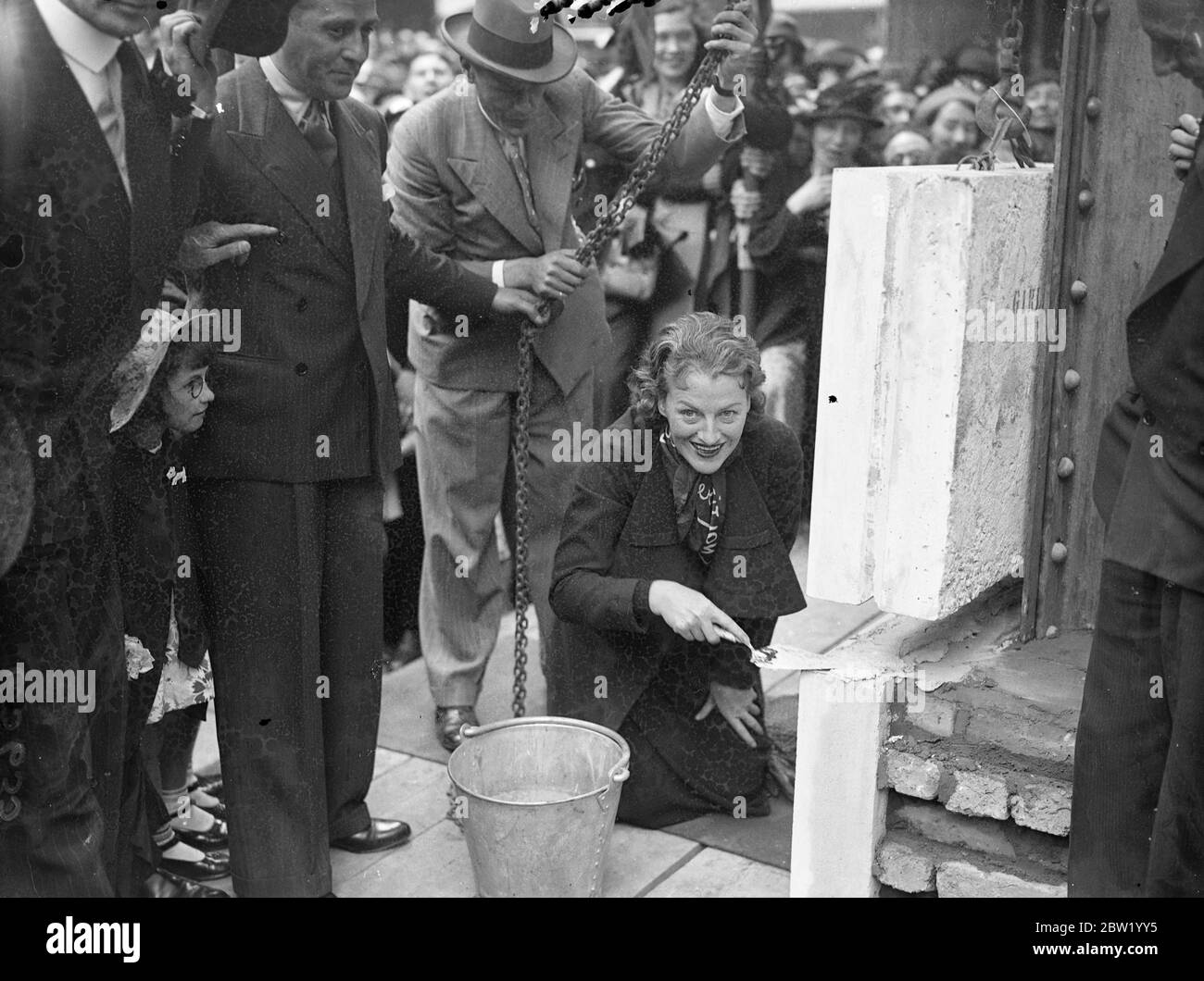 Gracie Fields lays foundation stone of new Prince of Wales Theatre. Gracie Fields, laid the foundation stone of the new Prince of Wales Theatre in Coventry Street. Even the West End traffic was brought to a stop when, in response to the crowds clamour, Miss Fields sang 'Sally'from a ladder. The scene resembled an episode from one of Gracie's own films. Photo shows, Miss Gracie Fields, laying the foundation stone.. 17 June 1937 Stock Photo