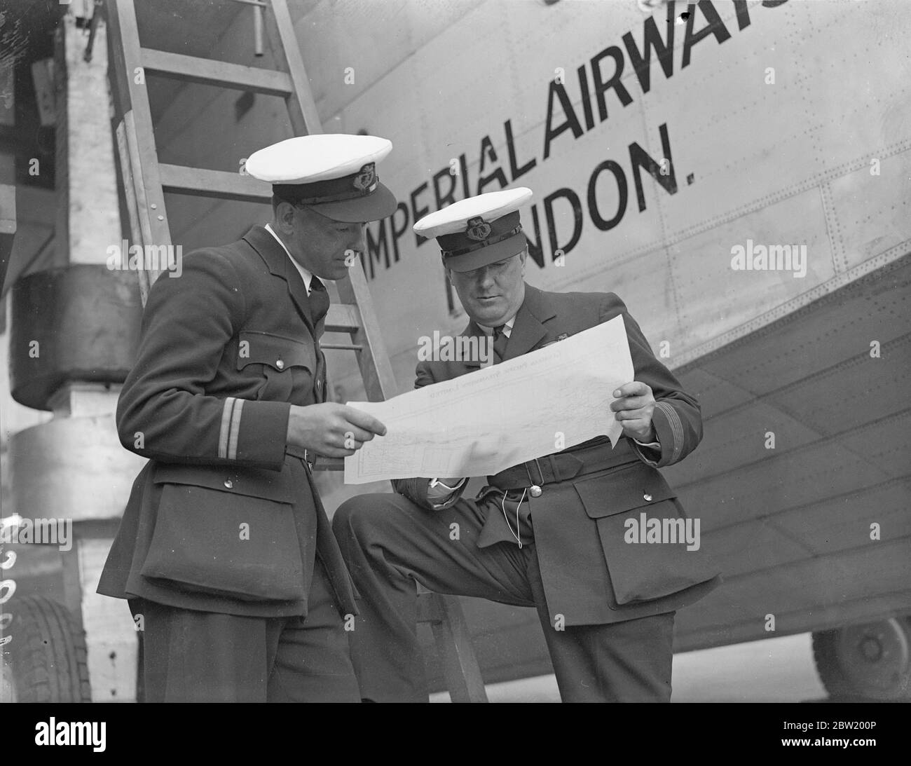 Captain A. S. Wilcockson (right) and First Officer G. H. Bowes studying the Atlantic route beside Caledonia at Hythe, Southampton in readiness for the first experimental commercial transatlantic crossing to be made by the flying boat Caledonia next week (June 24). 18 June 1937 Stock Photo