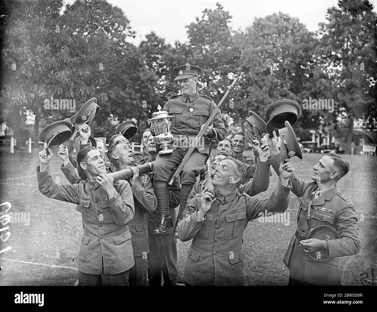 Corporal J. White of the Rifle Brigade won the Army rifle championship at Bisley. He carried off the King's Medal, the Watkin Cup, and the Army Rifle Association's gold jewel. His aggregate of 418 was seven points better than that of the last year's winner. Corporal White chaired and cheered after his victory. 1 July 1937 Stock Photo
