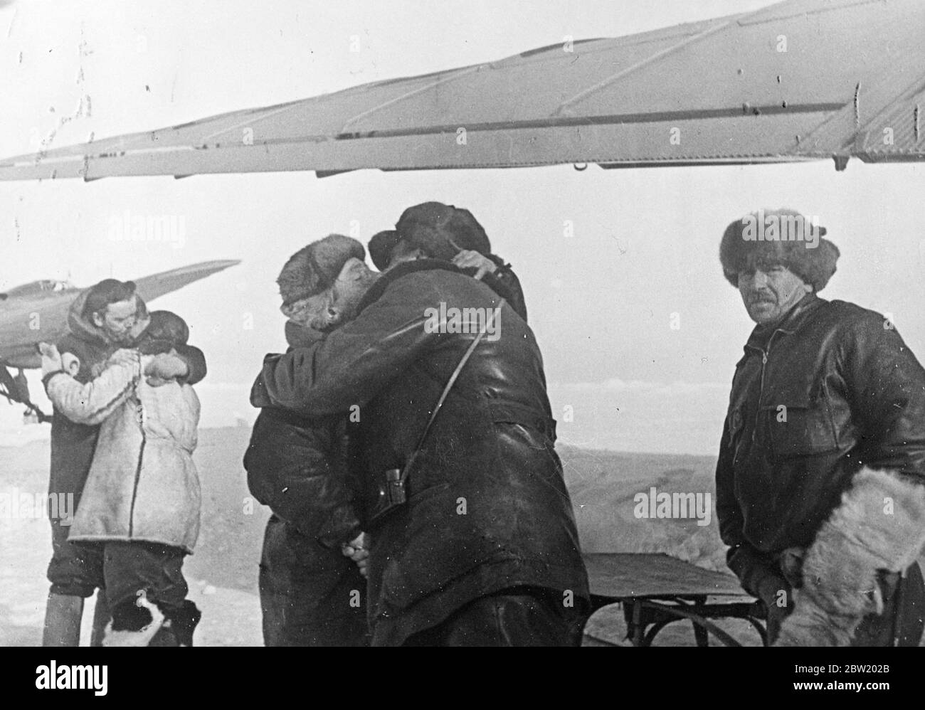 These pictures, the first ever made at the North Pole, were flown to Moscow and from there to London. The Soviet scientific expedition led by Professor Otto Schmidt has succeeded in establishing on an ice floe in the frozen wilderness from which valuable scientific information and regular weather reports are now being sent by radio for the first time in history. Members of the expedition taking an affectionate leave of the party which are leaving the ice floe. On left E. Krenkel, the radio operator, Professor Otto Schmidt in centre taking leave of Papanin, head of the expedition, and polar fly Stock Photo