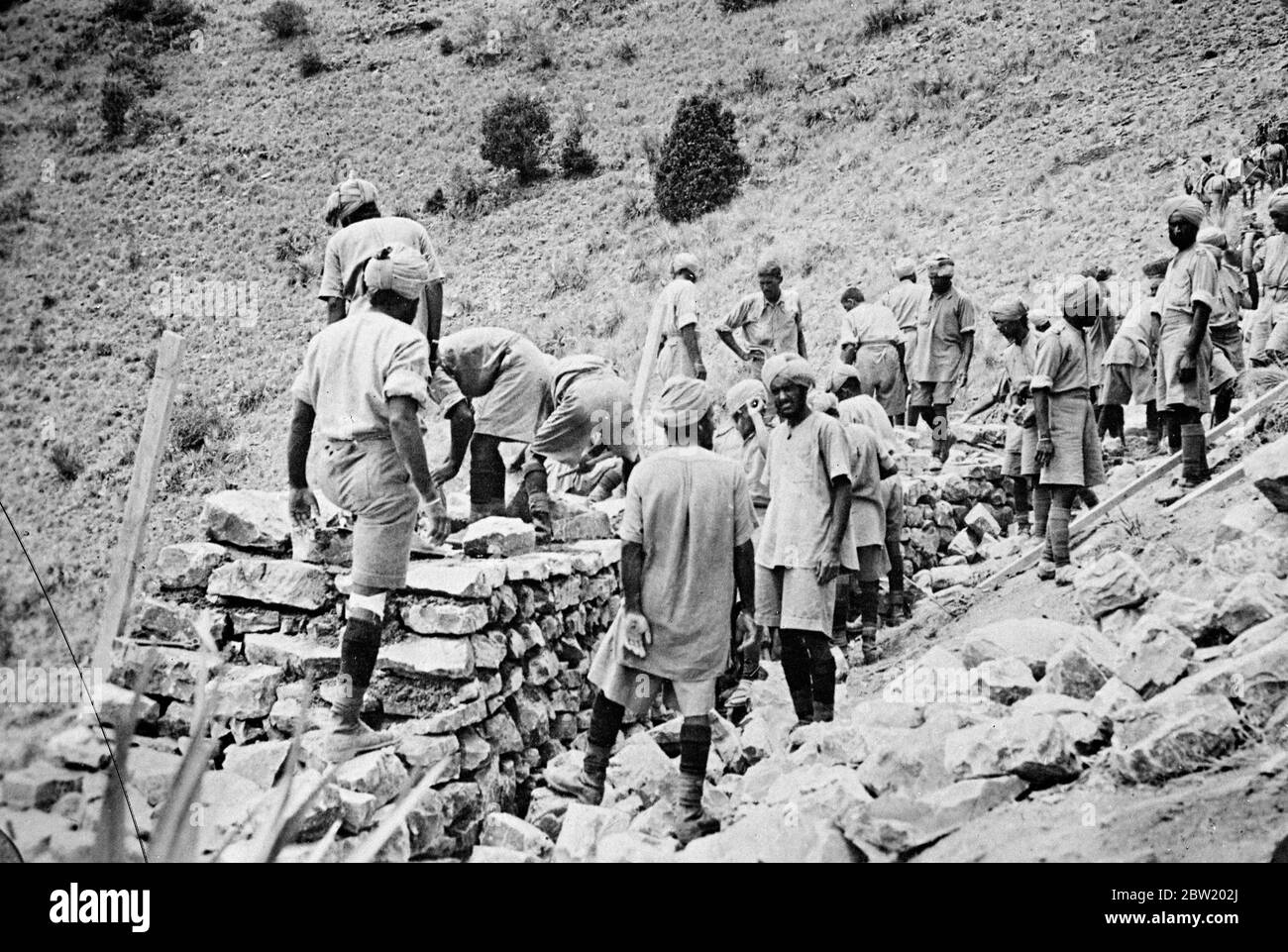 British forces are now consolidating their position on the North West Frontier of India, where they had been waging a big scale campaign against rebellious tribesmen stired up by the elusive Fakir of Ipi. British Indian troops building stone defences to strengthen their position on the road from Dosalli to Ghariom. 19 July 1937 Stock Photo