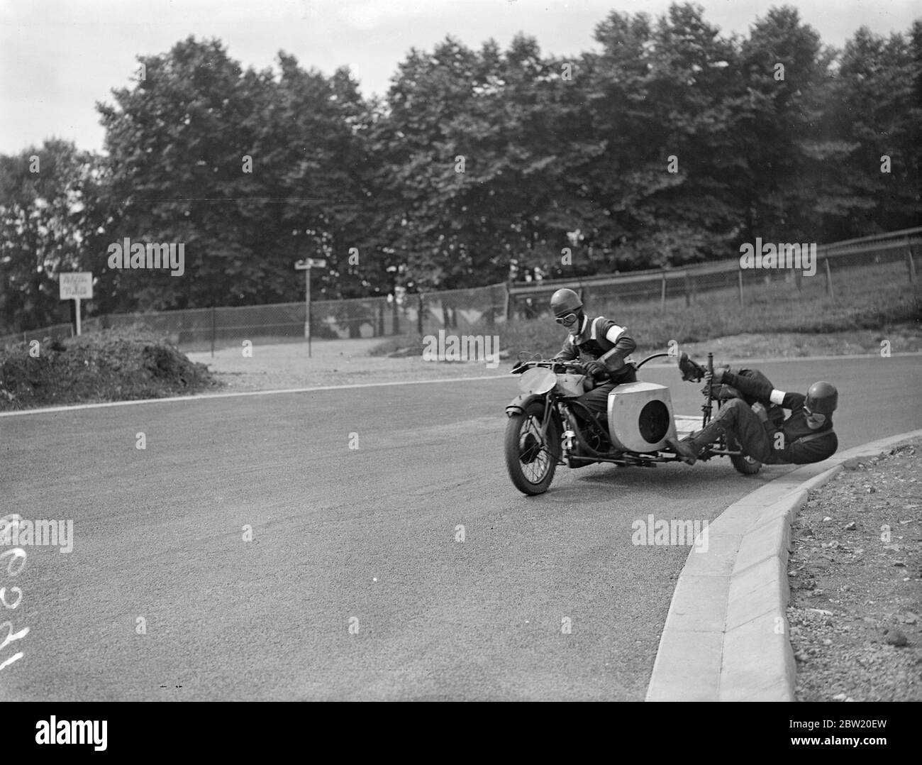 Motor cyclists had a final practice on the Crystal Palace Road Racing Circuit for the London Grand Prix meeting today (Saturday). Here the passenger is performing an acrobatic to keep balance as B. H. Kimberly (Norton) round the bend on the track. 17 July 1937. Stock Photo