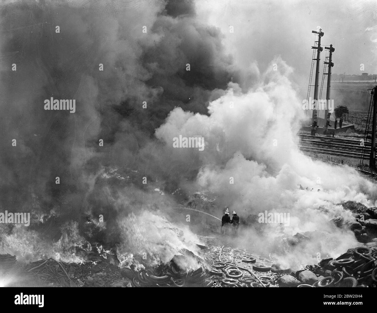 Dense clouds of smoke rising from the burning rubber as firemen fought the blaze which raged for hours at a rubber tyre dump in Markfield Road, Tottenham. 29 June 1937 Stock Photo