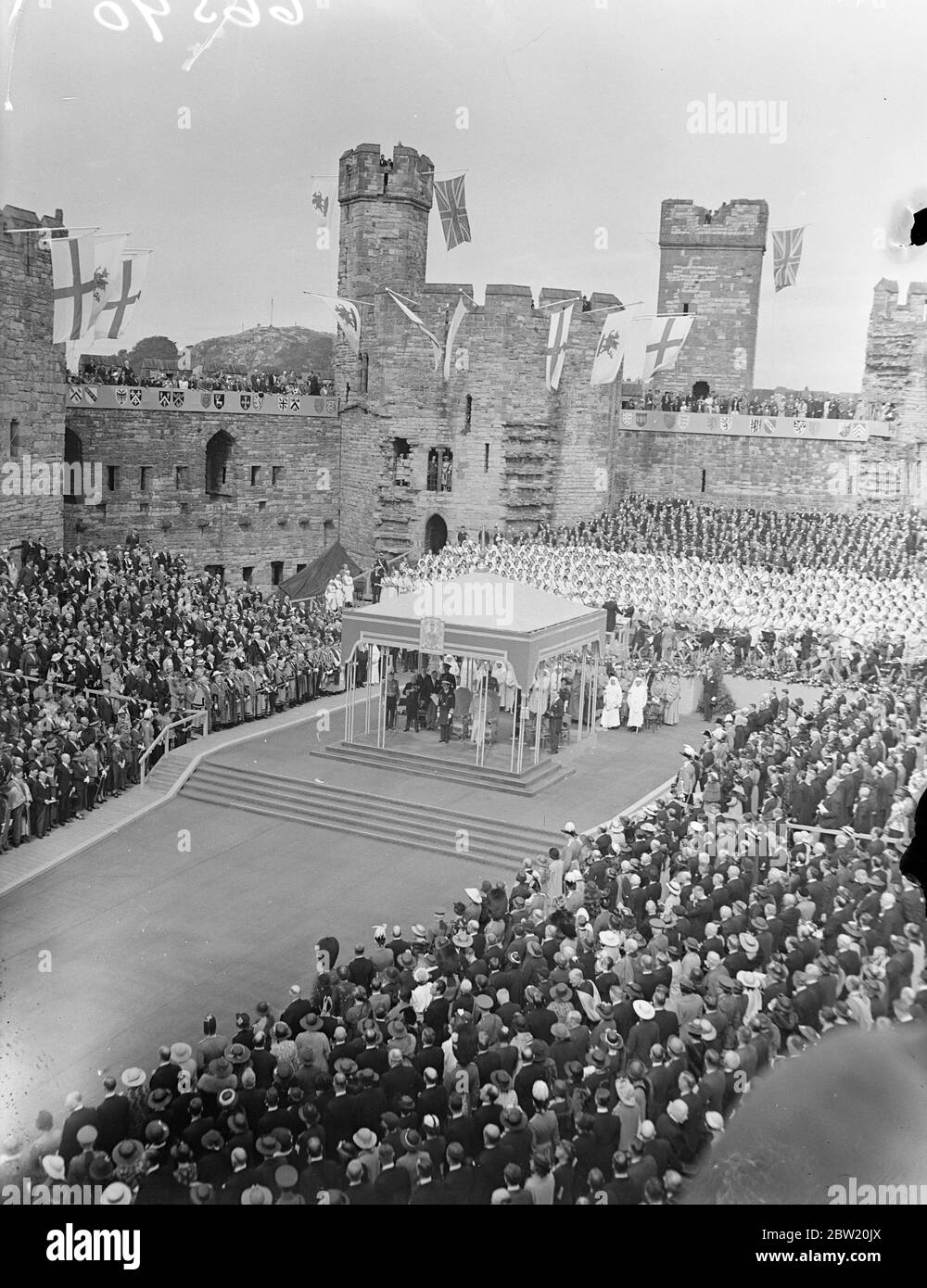 Standing on the spot from which according to legend, the first Prince of Wales was shown to the chieftains, the King and Queen showed themselves to the people of Wales at the historic Caernarvon Castle at the end of their two-day tour of Wales. The King and Queen listening to a choir of 800. With their Majesties is Mr David Lloyd George, the Constable of the Castle. The background is the Eagle Tower. 15 July 1937. Stock Photo