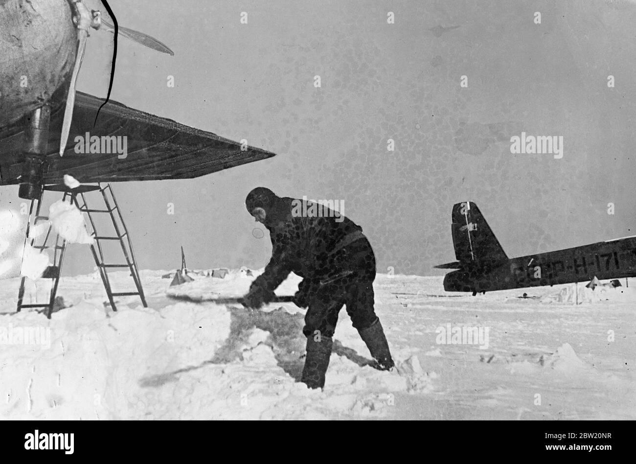 These pictures, from the North Pole, were flown to Moscow and from there to London. The Soviet scientific expedition led by Professor Otto Schmidt successfully established a scientific village on an ice floe in the frozen wilderness from which valuable scientific information and regular weather reports are now being sent by radio for the first time in history. M. Vodopyanov pilot of the expedition, cleaning snow from the floe in front of his plane. 30 June 1937 Stock Photo