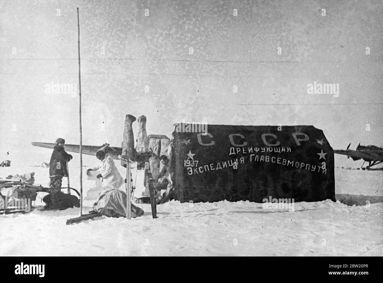 These pictures, the first ever made at the North Pole, were flown to Moscow and from there to London. The Soviet scientific expedition led by Professor Otto Schmidt has succeeded in establishing on an ice floe in the frozen wilderness from which valuable scientific information and regular weather reports are now being sent by radio for the first time in history. The main tent of the expedition bearing the inscription that reads: USSR, the Drifting Expedition of the Chief Administration of the North Sea Route -1937. 28 June 1937 Stock Photo