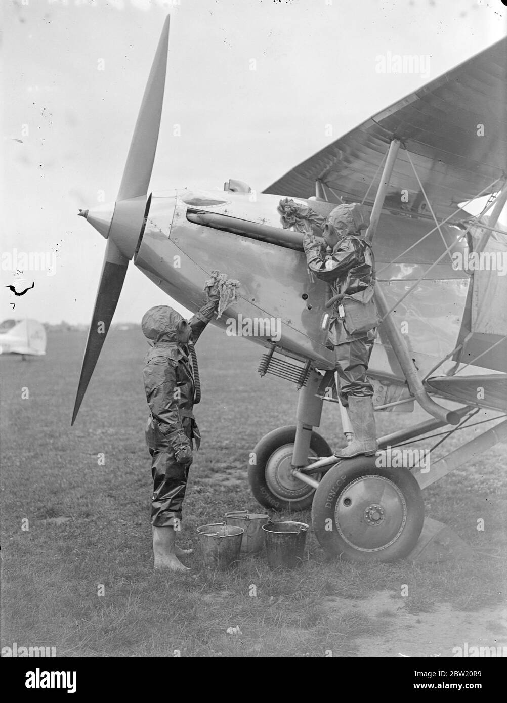 Men wearing the latest anti-gas clothing decontaminating a plane. The clothing is proofed against air and gas that it can only be worn for three quarters of an hour with comfort, was used by men taking part in the coastal defence exercises St lee-on-Solent aerodrome. 15 July 1937 Stock Photo