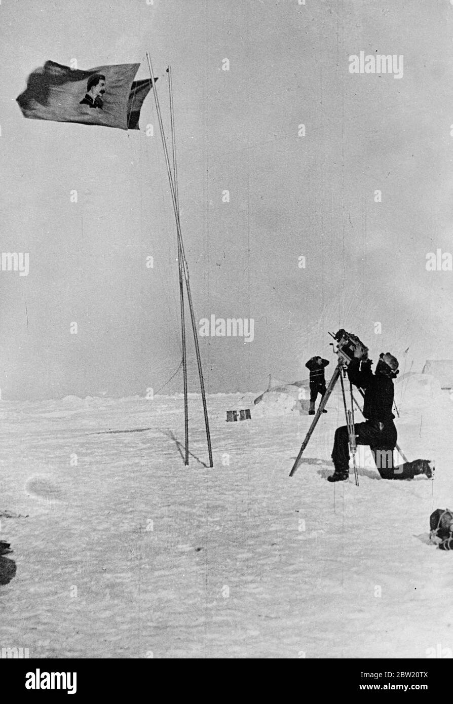 These pictures, the first ever made at the North Pole, were flown to Moscow and from there to London. The Soviet scientific expedition led by Professor Otto Schmidt has succeeded in establishing on an ice floe in the frozen wilderness from which valuable scientific information and regular weather reports are now being sent by radio for the first time in history. A flag bearing a portrait of Stalin and the flag of the Soviet Union fluttering side-by-side at the North Pole. A member of the expedition is seen operating a cine camera. 28 June 1937 Stock Photo