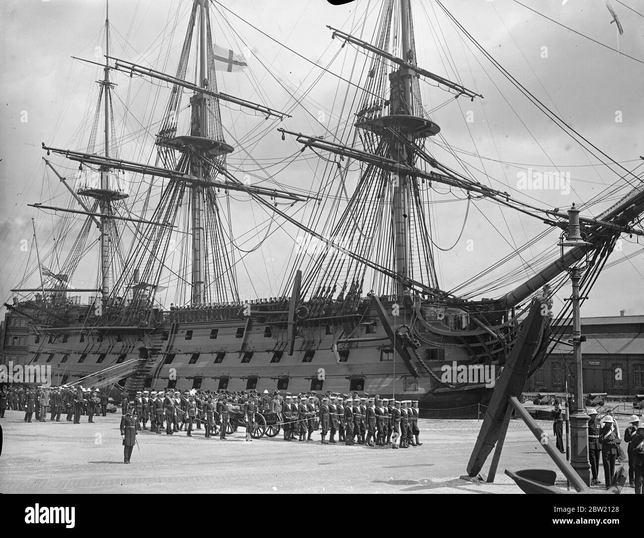 With full naval honours, the body of Admiral Sir William Fisher, former Commander-in-Chief at Portsmouth, was taken on board the destroyer Curacoa from Portsmouth for burial at sea. The cortege passing through the dockyard at Portsmouth to the destroyer Curacoa showing the ship Victory in the background. 29 June 1937 Stock Photo
