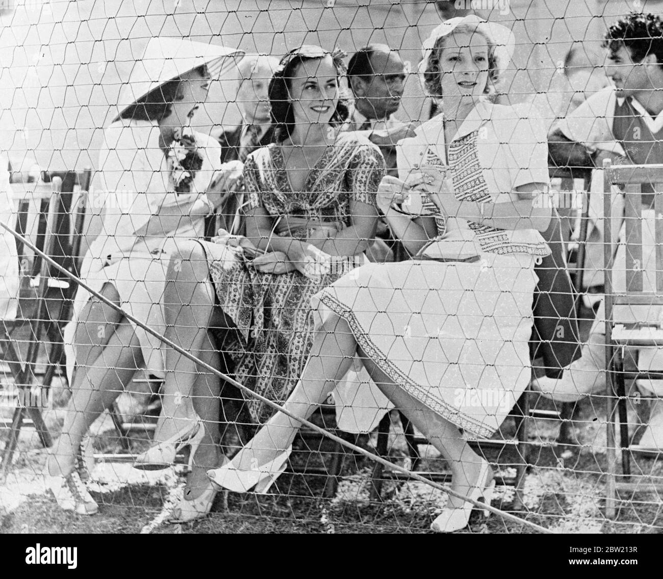 The world's funniest tennis match was played on the court of the Beverly Hills Tennis Club, Beverly Hills, California, between Charlie Chaplin, partnered by Fred Perry and John Marks playing with Ellsworth Vines. Perry and Chaplin won 6 - 1, 9 - 7. Photo shows: Mrs Douglas Fairbanks (formerly Lady Ashley); Paulette Goddard, Chaplin's leading lady; and Helen Vinson, wife of Fred Perry watching the game. Back row, left-to-right: Sid Grauman; Douglas Fairbanks and Gilbert Roland. 19 July 1937 Stock Photo