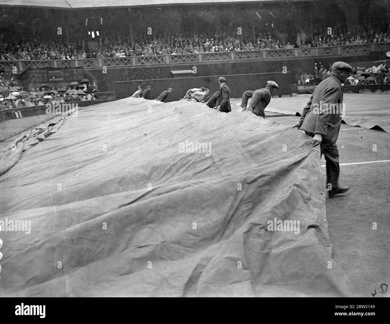 For the first time since the championships commenced, rain stopped play on the Central Court at Wimbledon, during the match between Fru Sperling, the Danish favourite for the women's title, and Miss Alice Marble, the American women's champion. Covering the Centre Court against the rain. 29 June 1937 Stock Photo