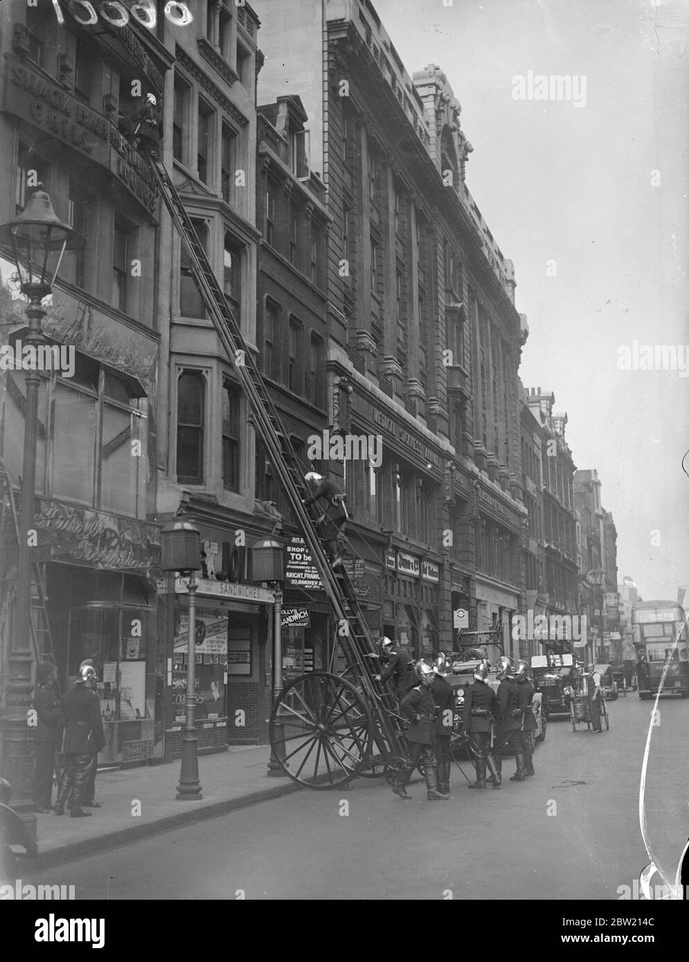 Firemen mounting the escape to enter the window at the scene of the fire in High Holborn this morning (Sunday). Two escapes and several pumps were called to the fire, which is believed to have been caused by the explosion a refrigerator over premises occupied by a restaurant. 27 June 1937 Stock Photo