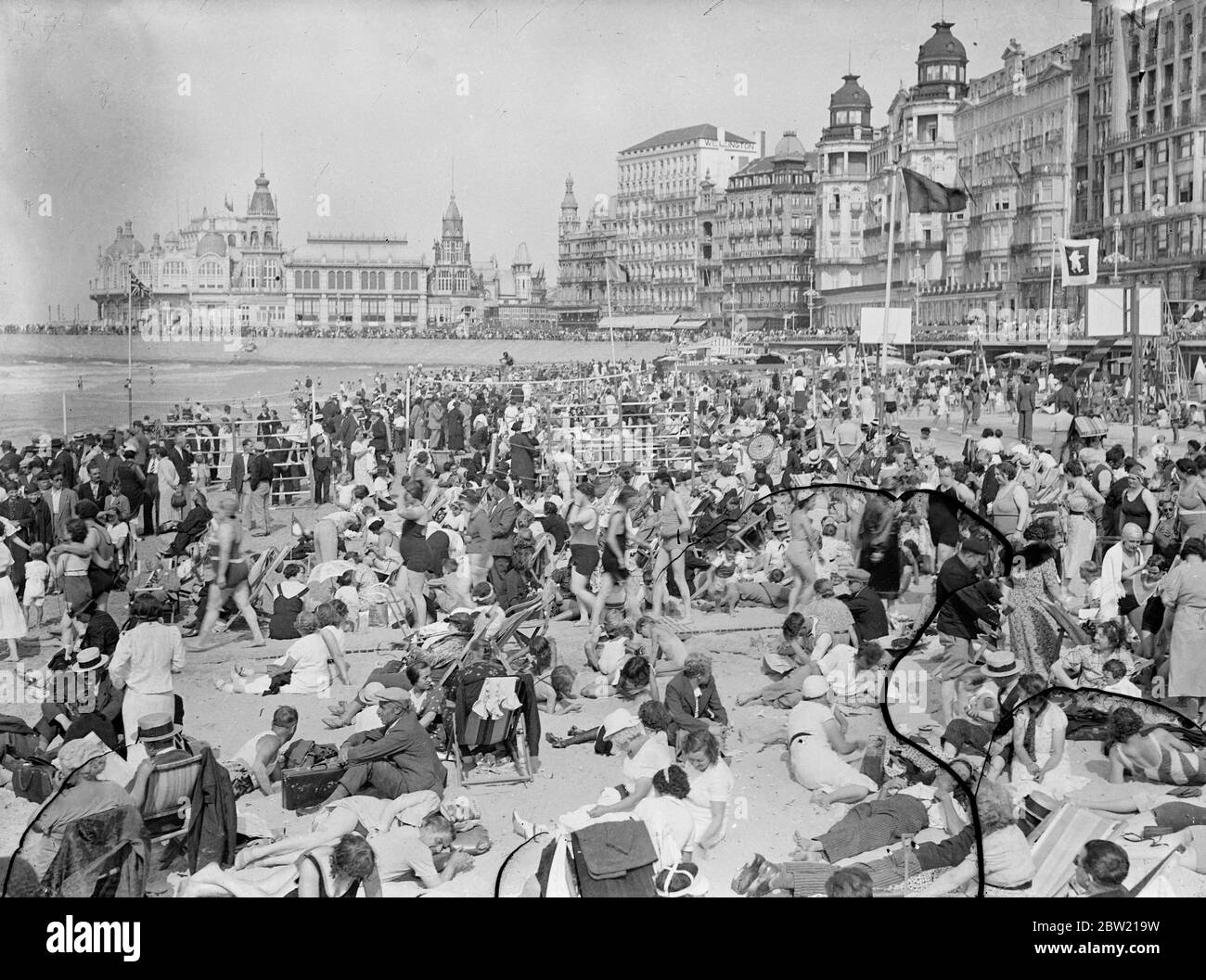 The holiday crowd, rivalling any scene on an English resort, thronging the beach at Ostend, Belgium. In the background is the Kursaal from which many concerts have been broadcast to England. 14 August 1937. Stock Photo