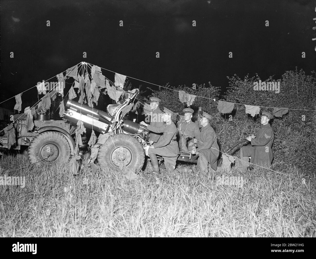 A camouflaged gun - belonging to the 82nd Field Battery in action. Throughout a night a fierce struggle in which tanks and artillery participated has been raging for Rivey Hill near Balsham, Cambridgeshire. In the East Anglian War, Eastland made a dawn attack with the 2nd Division Artillery and 4th Battalion Royal Tank Corps. 27 August 1937 Stock Photo