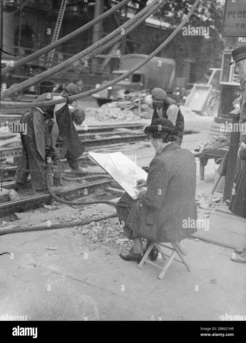 A woman artist found a noisy spot among the pneumatic drills as she sketched the final demolition work on the remains of old Waterloo Bridge. The workmen are shifting the tram tracks to the new tunnel made necessary by the demolition work. 2 September 1937 Stock Photo