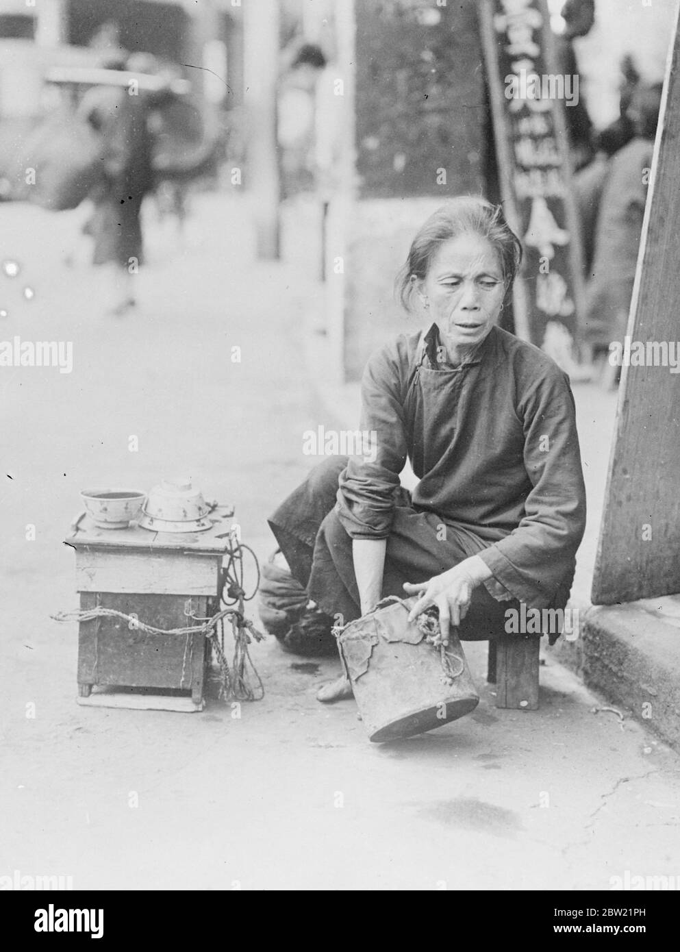 The same battle for existence that her country is now waging against Japan is mirrored in the emaciated, weary features of this old tea seller in the streets of Canton [Guangzhou], China. She earns only a few coppers a day and her main customers are the rickshaw boys whose gruelling job necessitates constant hydration. 31 August 1937 [?] Stock Photo