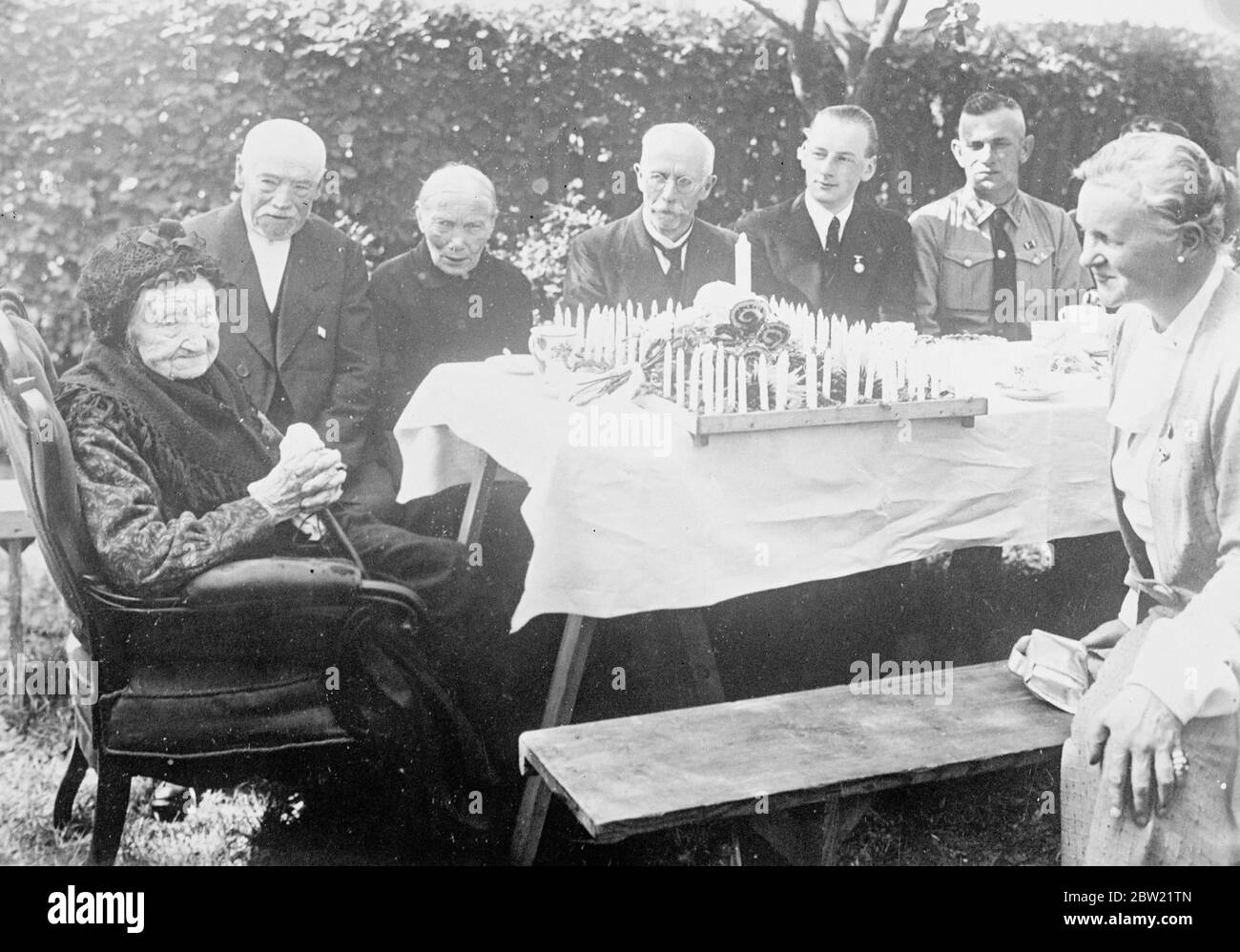 Germany's oldest woman, celebrated her 106 birthday at Sonnenborn in East Prussia. Despite her great age she does not wear glasses. Frau Wilhelmine Olschewski, seated before her birthday cake decorated with 106 candles with some of her numerous descendants. 30 August 1937 Stock Photo