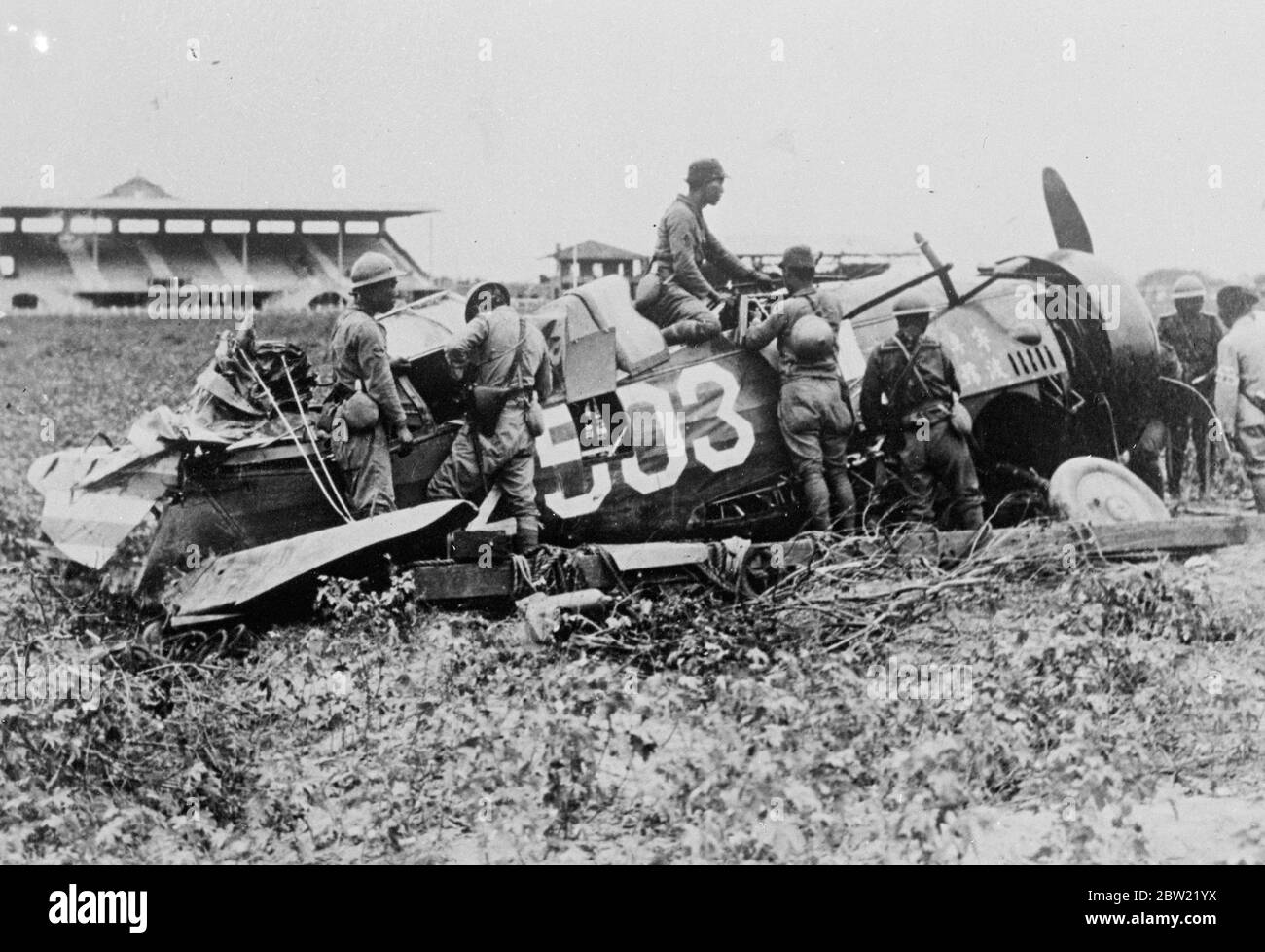 Delighted Japanese soldiers inspecting the wreckage of a Chinese warplane which was brought down by the forces at the racecourse and polo grounds near the Civic Centre at Shanghai.. 4 October 1937. Stock Photo