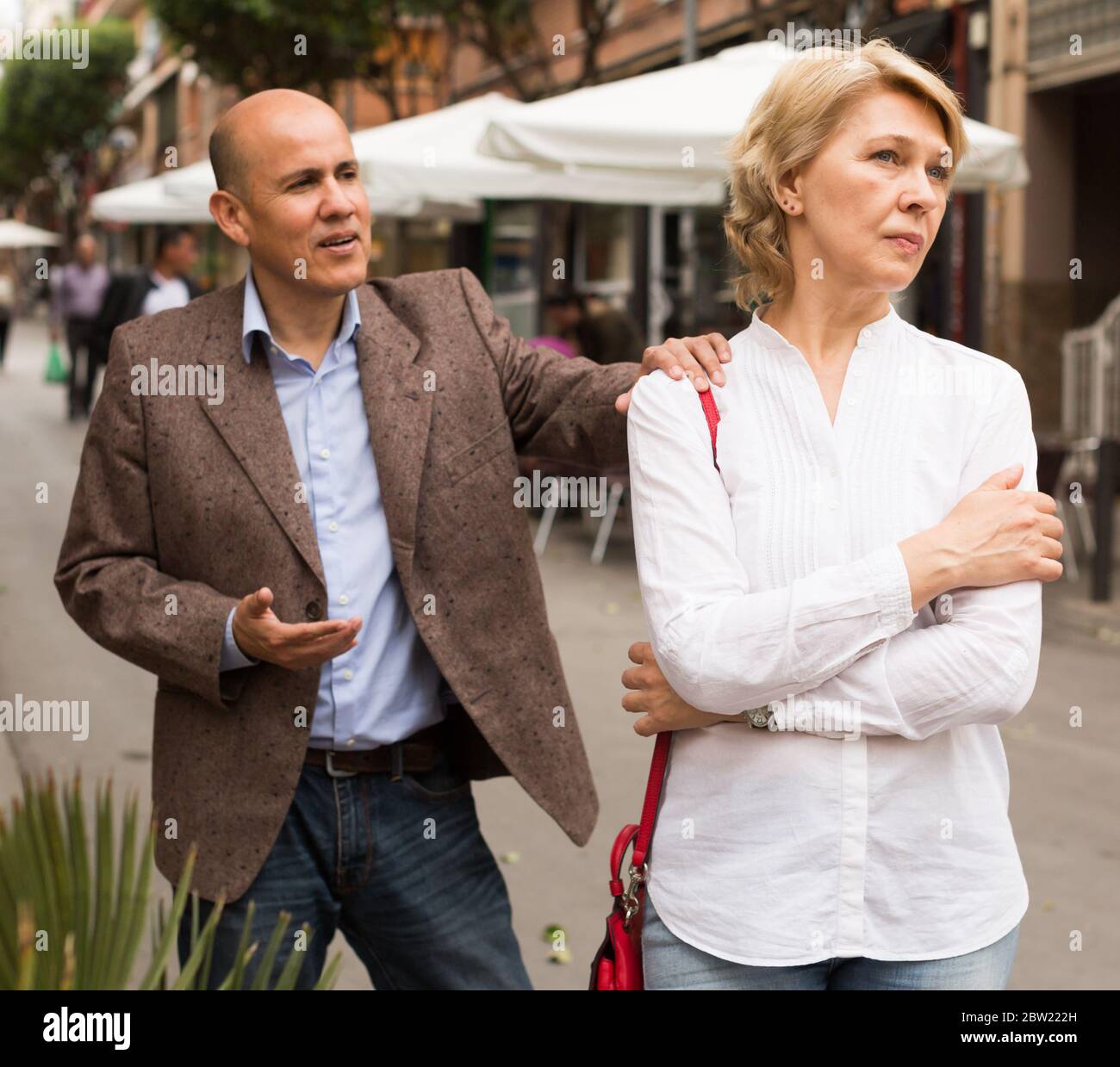 closeup of angry retiree blond woman being sad with man outdoors Stock Photo